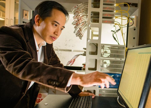 Zhongwei Chen pointing at laptop screen in a research lab
