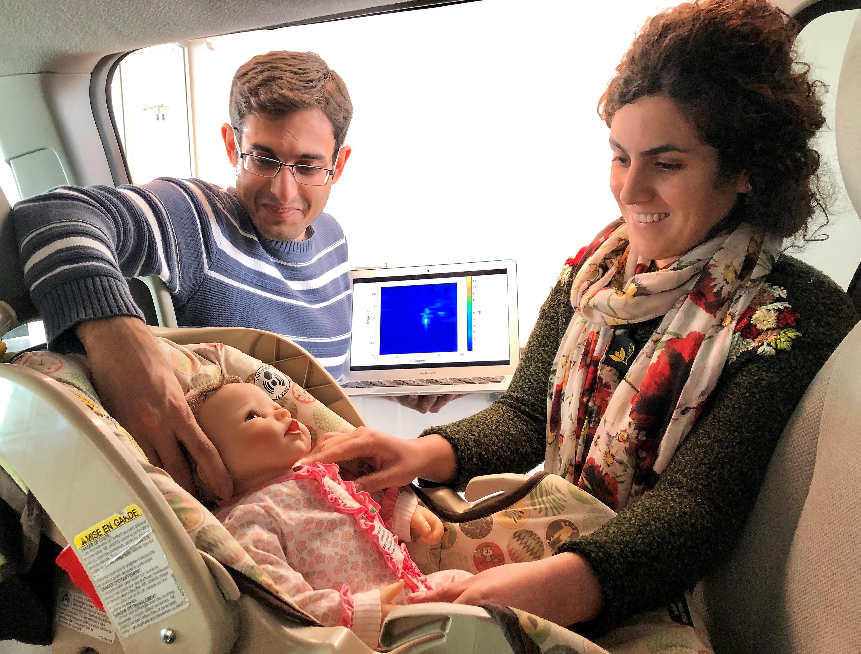 Graduate students Mostafa Alizadeh, left, and Hajar Abedi position a doll, modified to simulate breathing, in a minivan during testing of a new sensor.