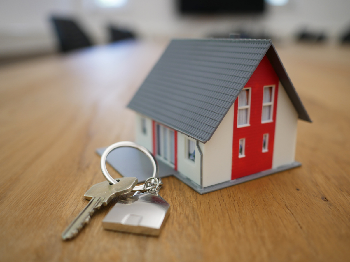 Small house model on table top with a set of keys next to it