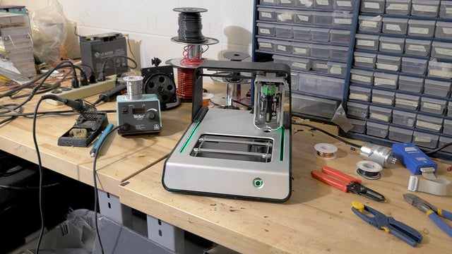 V-One circuit board printer sitting on tool bench surrounded by tools