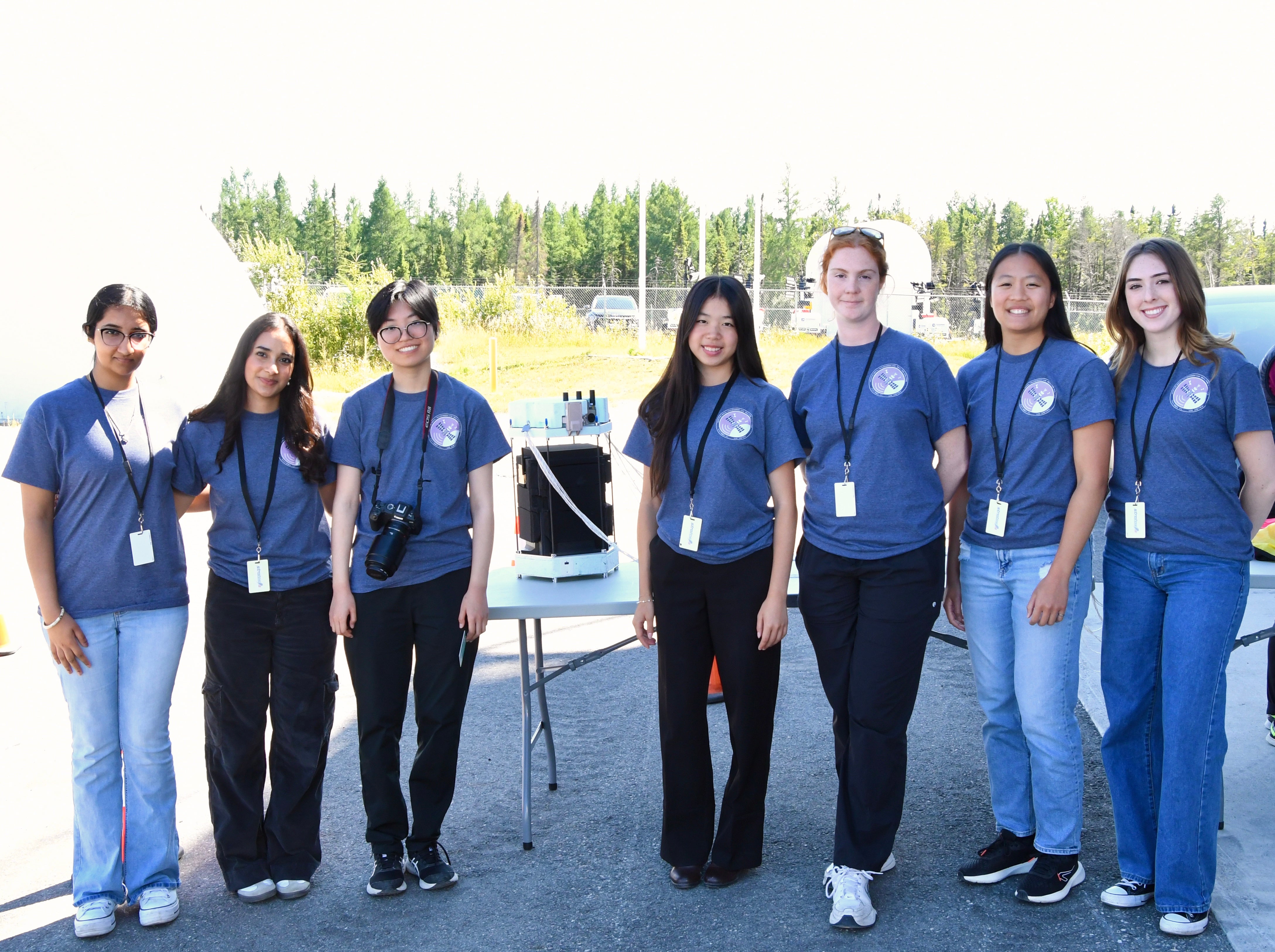 A group of female engineering students stand outside beside their project.