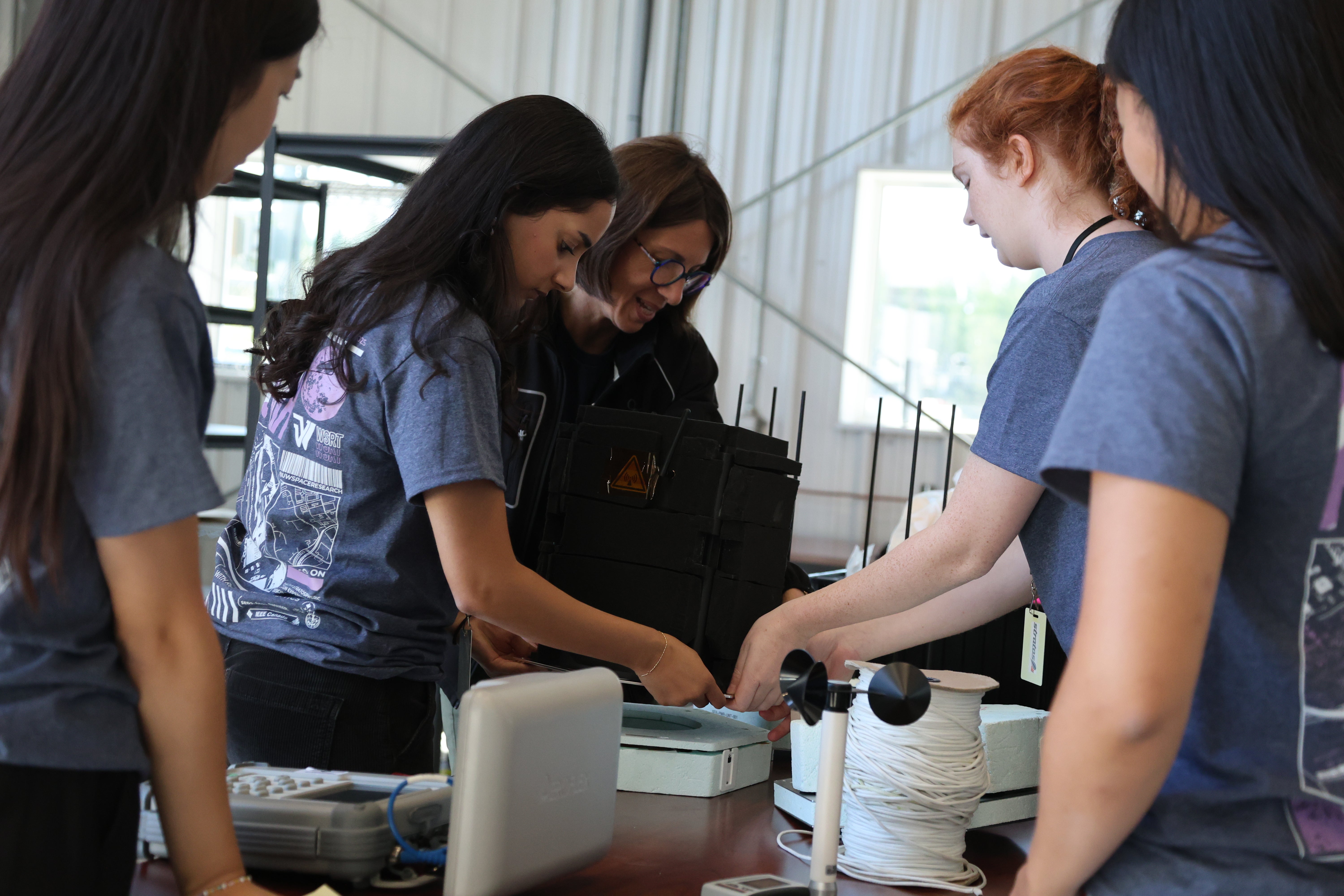 Female engineering students assemble their experiment indoors.