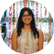 A young woman smiles at the camera in front of several vertical signs.