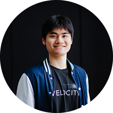 A young man smiles at the camera in front of a black background