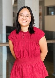 A young woman smiles at the camera, wearing a red dress.