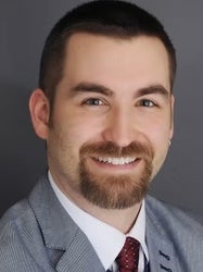 A white man with a beard smiles at the camera