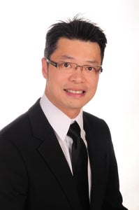 A young man smiles at the camera in a suit and tie