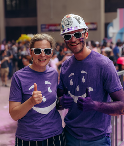 A woman gives a thumbs up, standing next to a young man with purple pant on his hands.