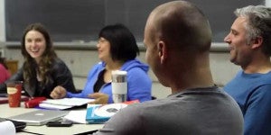 Graduate students around table talking and laughing