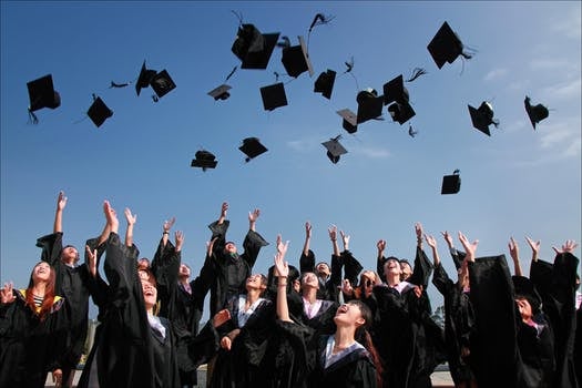 Photo of graduates tossing caps.