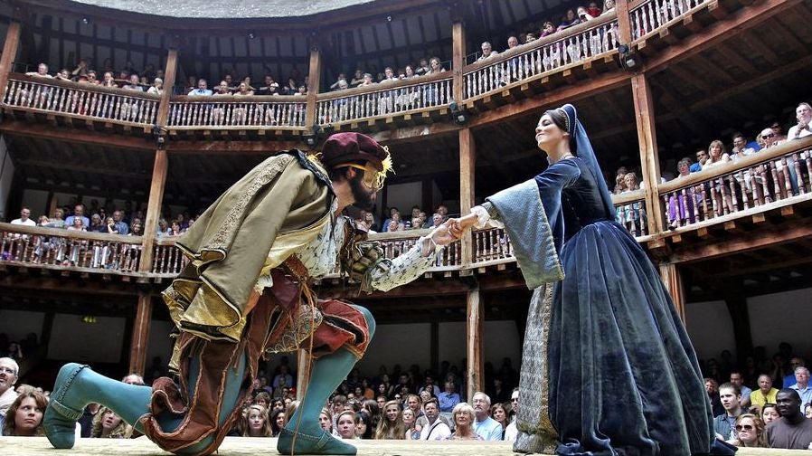 Photo of man kneeling before a woman in the Globe Theatre.