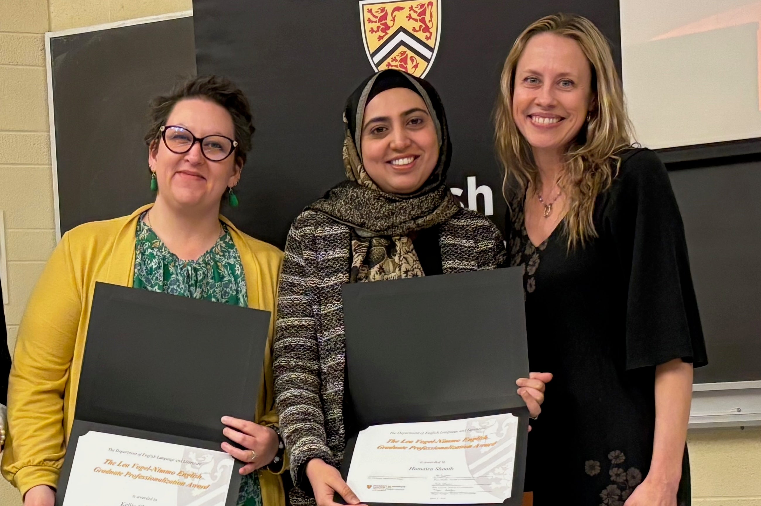 Kellie Chouinard and Humaira Shoaib receive the Lea Vogel-Nimmo English Graduate Professionalization Award from Dr. Jennifer Clary-Lemon.