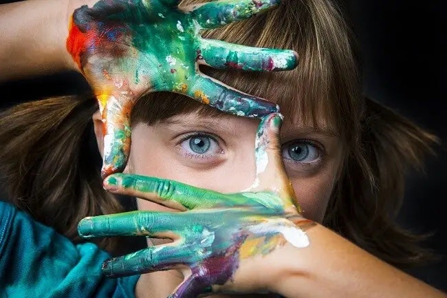 Woman looking out between painted hands.