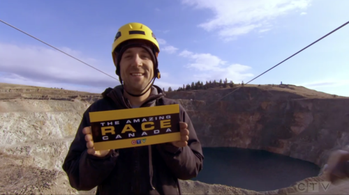 Brent Plumley holding Amazing Race Canada placard