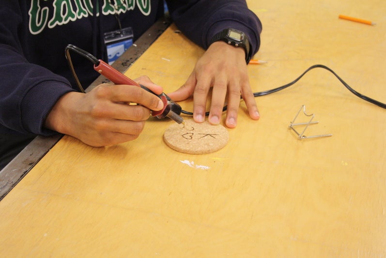Student hand making a coaster during an ENVigorate workshop.