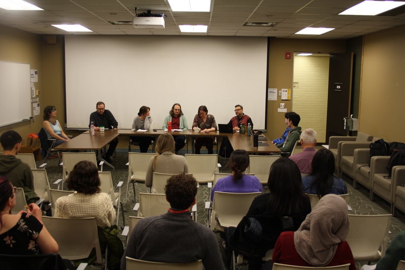 Panel of faculty members and PHD students face an audience in discussion.
