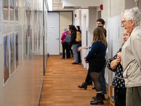 people admire a display of photos down a hallway