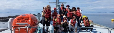 13 students wearing life vests onto of a barge look at the camera