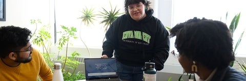 A student talks about work on a laptop as two others look on.