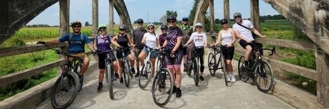 11 people on their bicycles standing on a bridge 