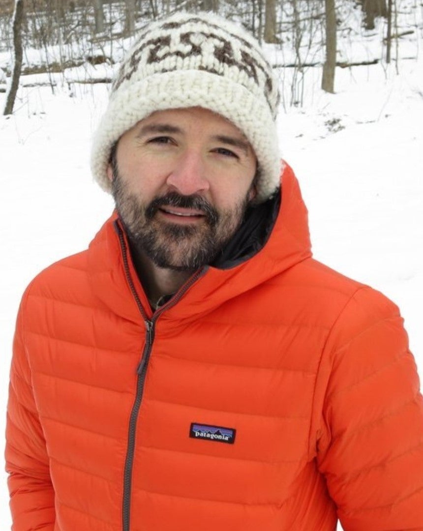 Andrew Trant wearing an orange winter jacket and off white toque