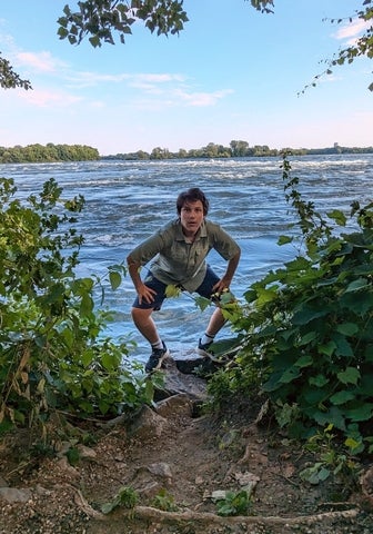 Michael is posing in front of a lake 