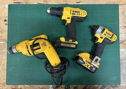 A regular, corded and compact drill on top a table.