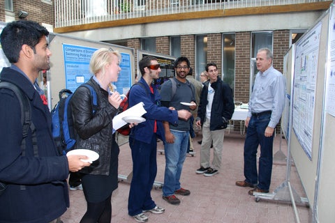 A professor presenting to a group of students during the poster session.