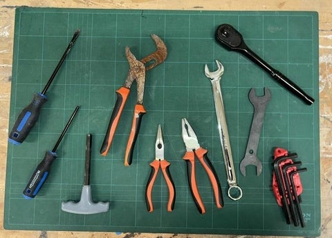 Screw drivers, pliers, wrenches, Allen keys and a socket wrench displayed on a table.