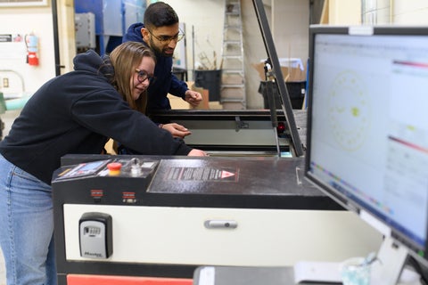 2 students working with the laser cutter