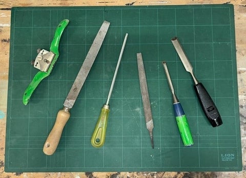 Chisels, files and wood scraper displayed on a table.