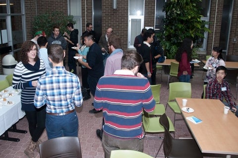 GIS Day participants mingling while eating cake.