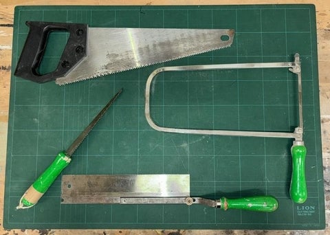 A wood, metal and scroll saw displayed on a table.