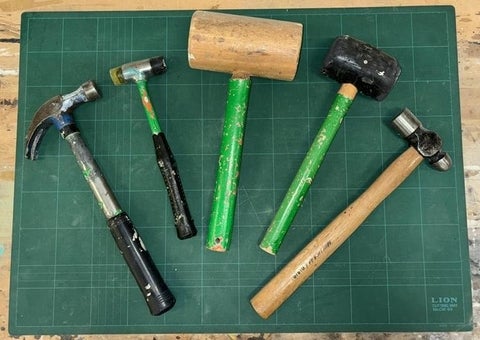 5 hammers and mallets of various sizes displayed on a table.