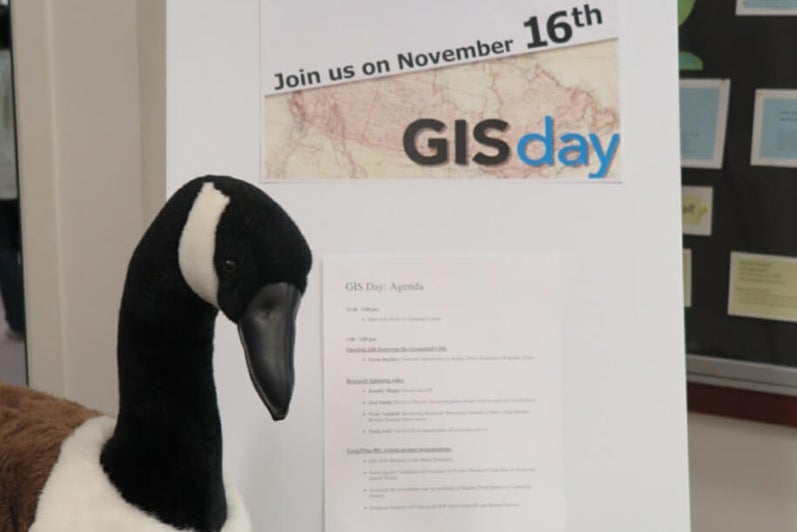 Goose looking at GIS Day 2016 poster.