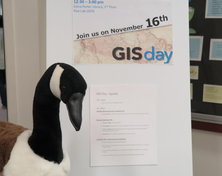 Goose looking at GIS Day 2016 poster.