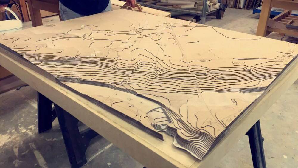 Terrain model made with laser cutter using contour lines and layering the cutouts on top of each other.