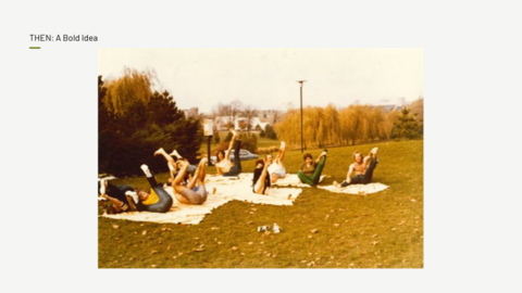 A group of people lie on blankets in a park, holding their legs up in a yoga pose.