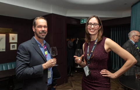 two people smiling and holding wine glasses