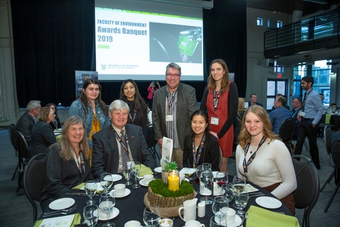 group of people posing for a photo with a slide deck in the background