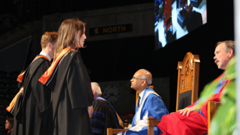 Student talking to Dean Frayne on the convocation stage. 
