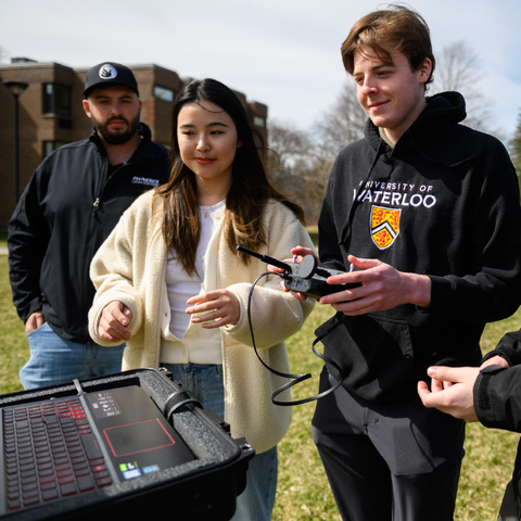 Geomatics students in the field around a laptop