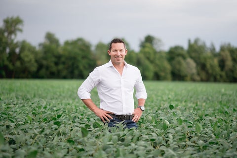 Man in white shirt sanding amongst a lush green field