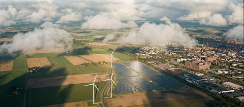 Aerial photograph of a city with a wind and solar farm Next door