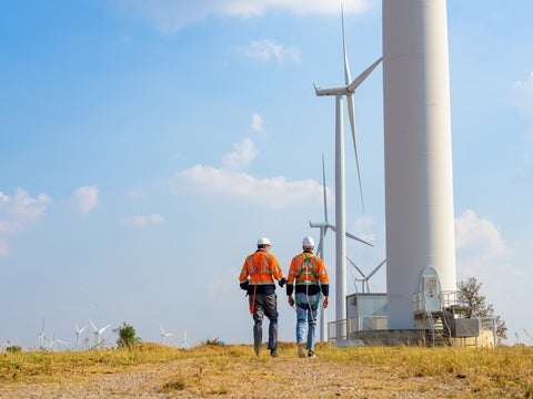 Two workers walking near windmills