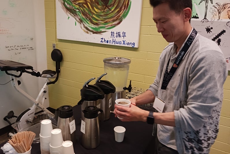 A person at a coffee station, pouring a cup of coffee. 