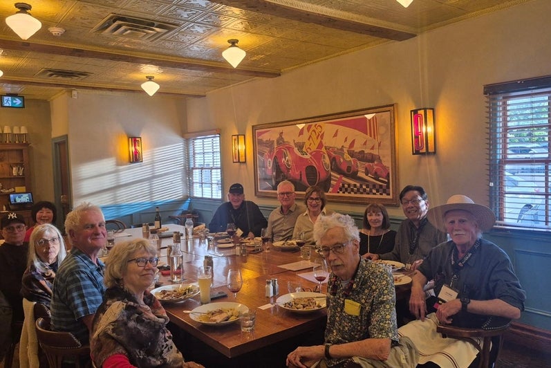 A group of people sitting around a large dining table in a restaurant, sharing a meal and engaging in conversation
