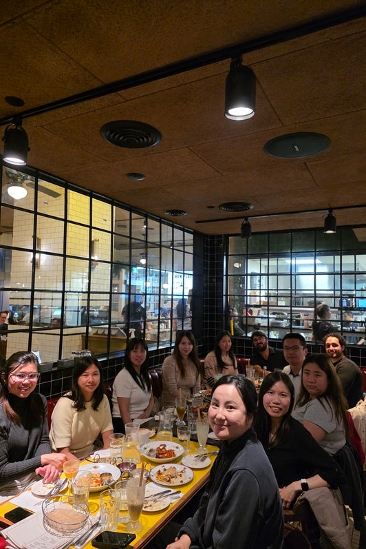A diverse group of people sitting at a restaurant table, smiling. 