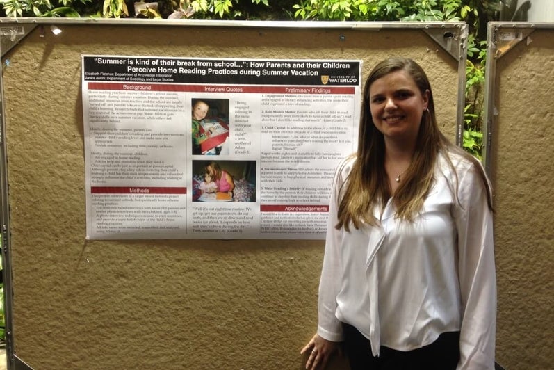 A university student standing in front of a research poster