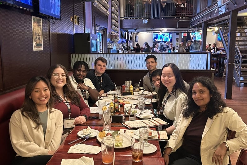 A group of people sitting around a table in a restaurant, with food and drinks on the table.